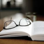 Open book with reading glasses placed on top, symbolizing learning and understanding of tax and accounting concepts.