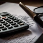 Desk setup with glasses, calculator, notebook, and pen representing tools used in professional bookkeeping services