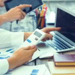 Professional reviewing financial records on a laptop with calculator, symbolizing modern bookkeeping services