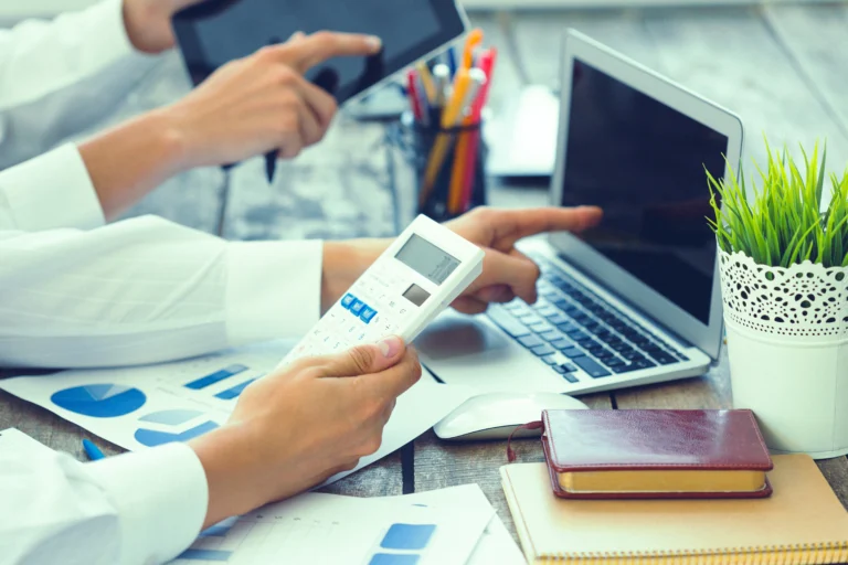 Professional reviewing financial records on a laptop with calculator, symbolizing modern bookkeeping services
