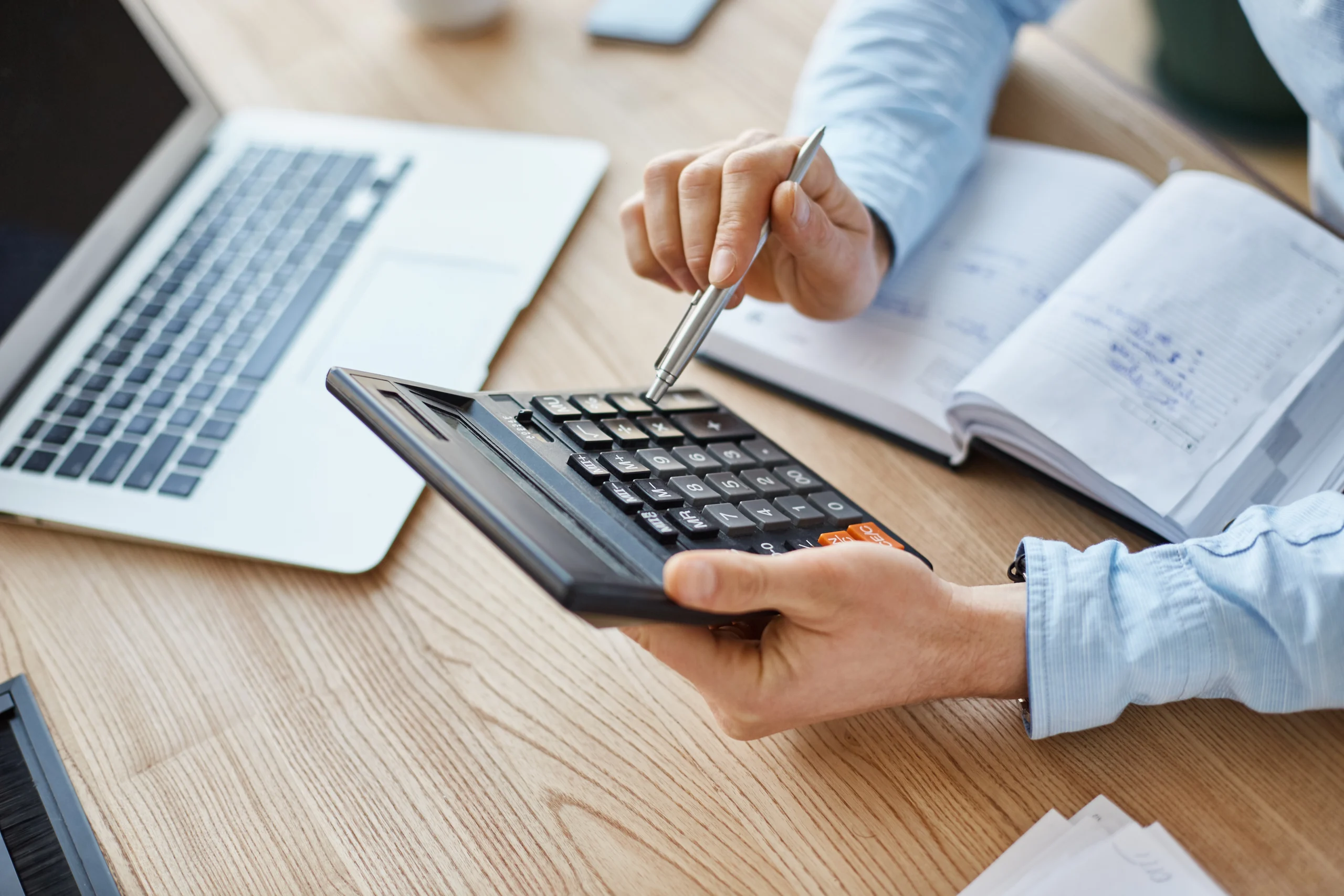 Person working on bookkeeping in Canada with a laptop, calculator, and pen on a desk