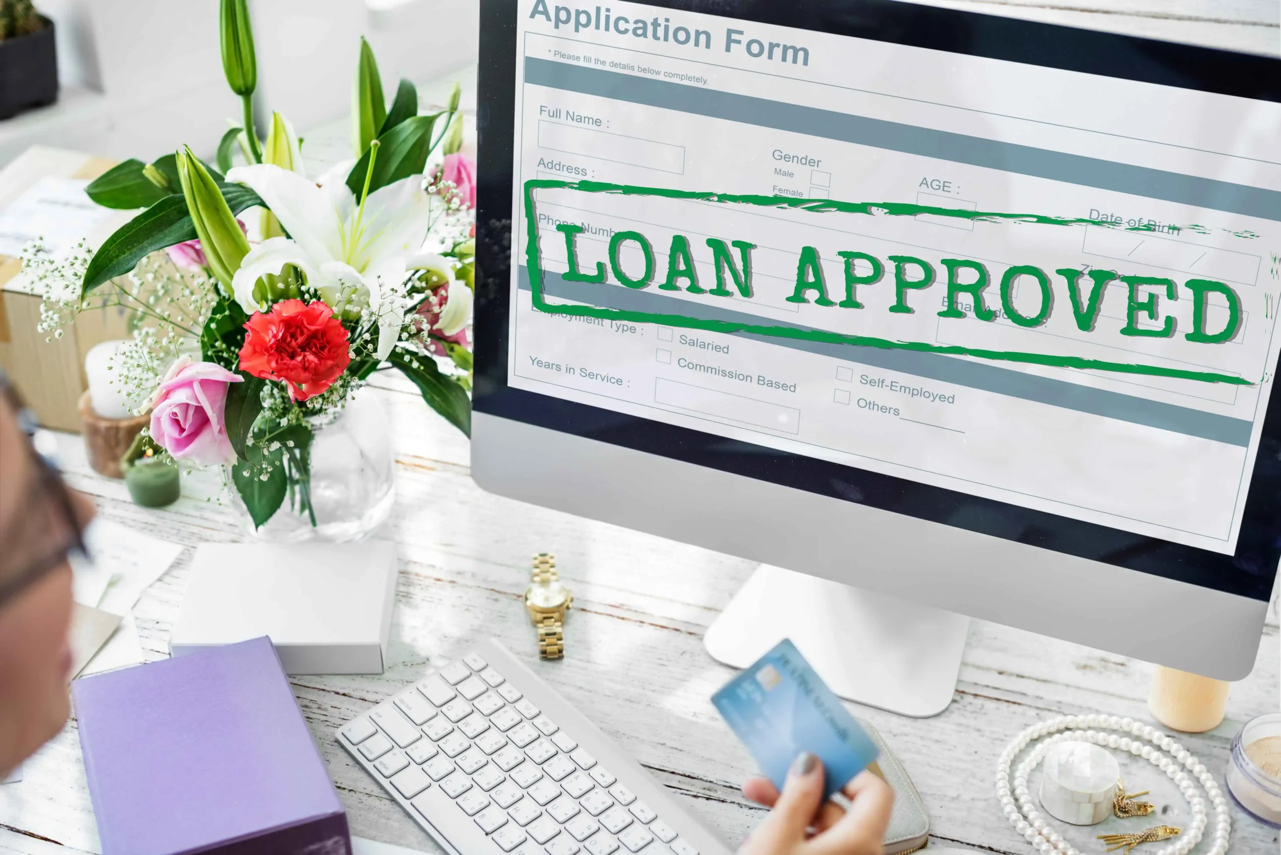 A person applying for a business loan with a “Loan Approved” screen in the background, highlighting the role of bookkeeping for business loans in successful applications.