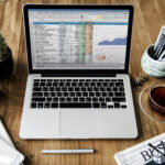 QuickBooks online advanced dashboard displayed on a laptop with coffee and notebook nearby